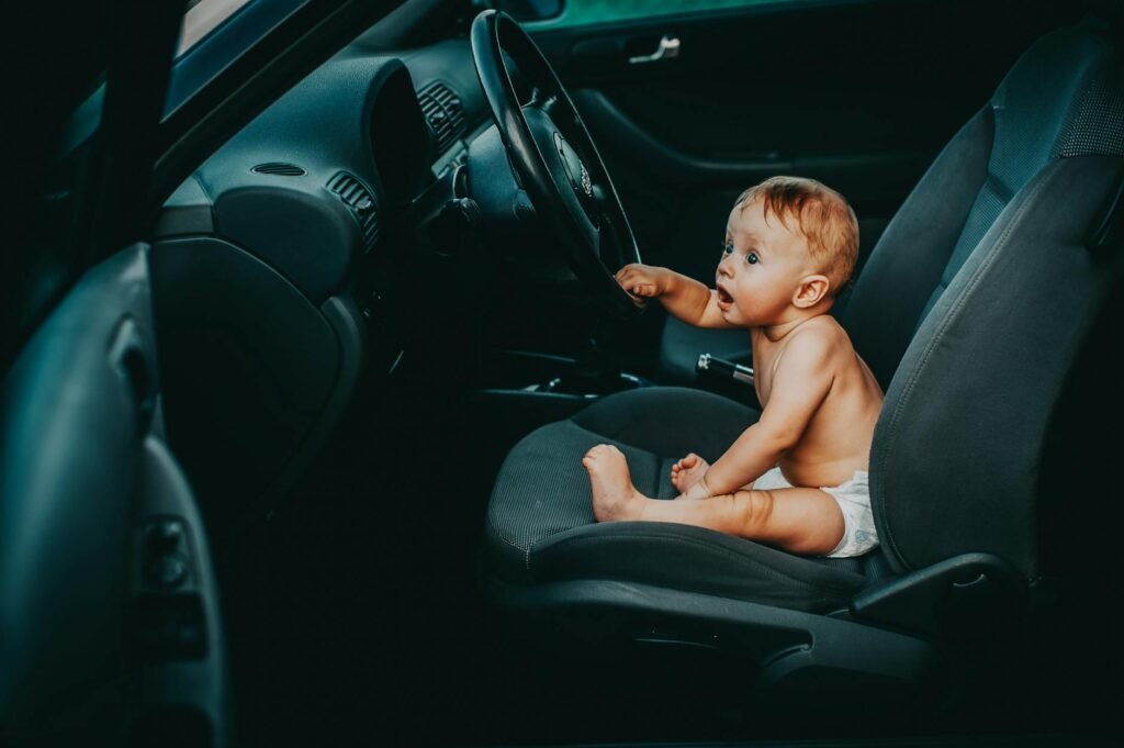 baby sitting by steering wheel in car